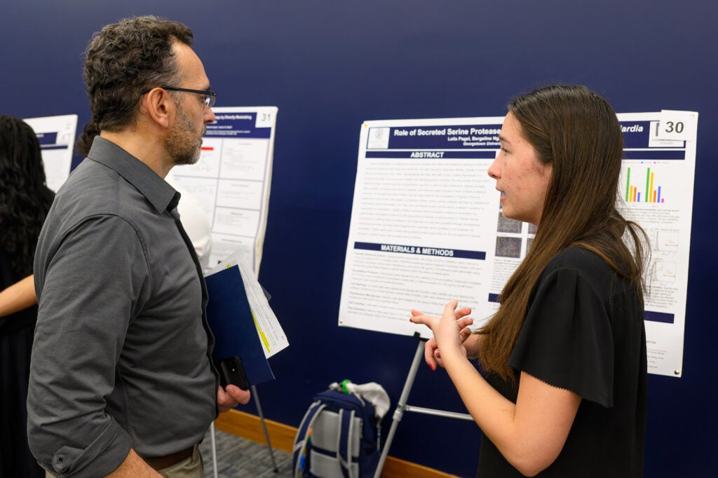 A student explains her poster to Pablo Irusta