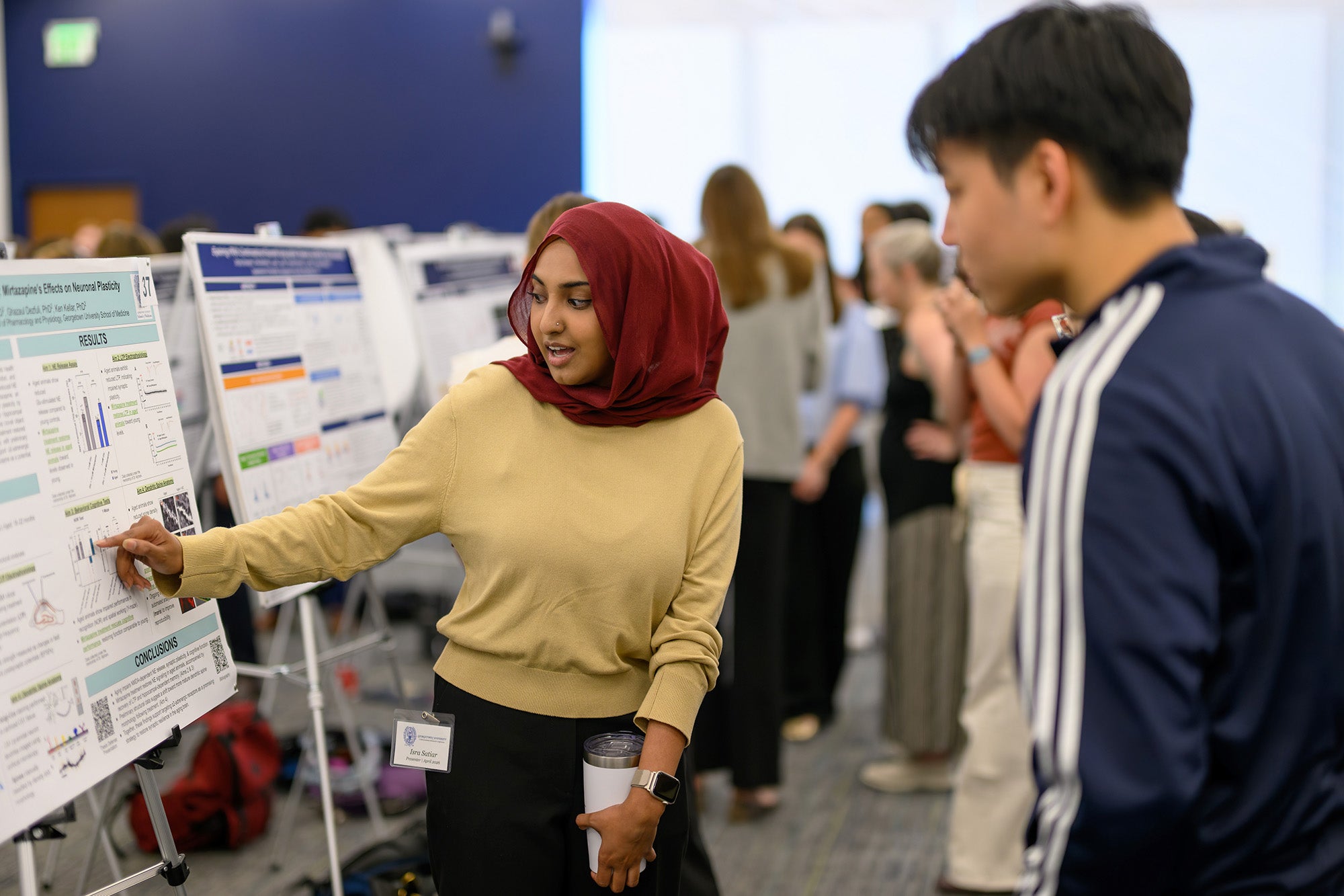 A student explains her poster to a conference attendee