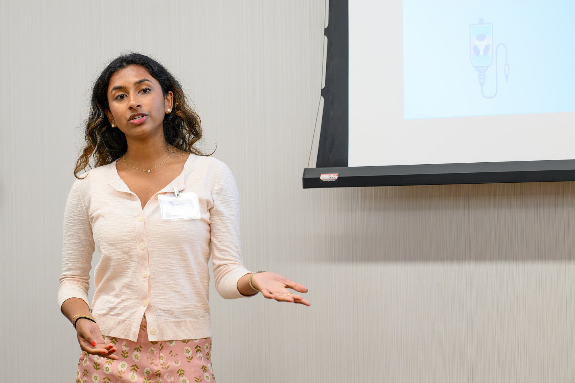 A student speaks with a display screen visible behind her