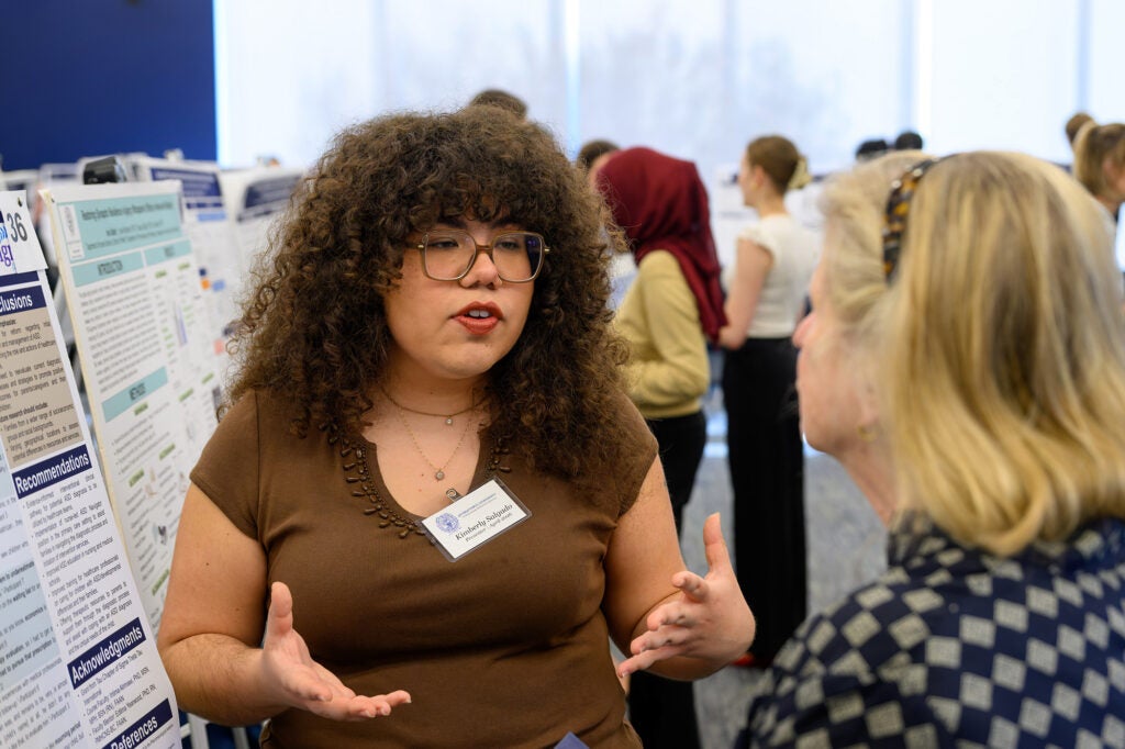 A student explains her poster to a conference attendee