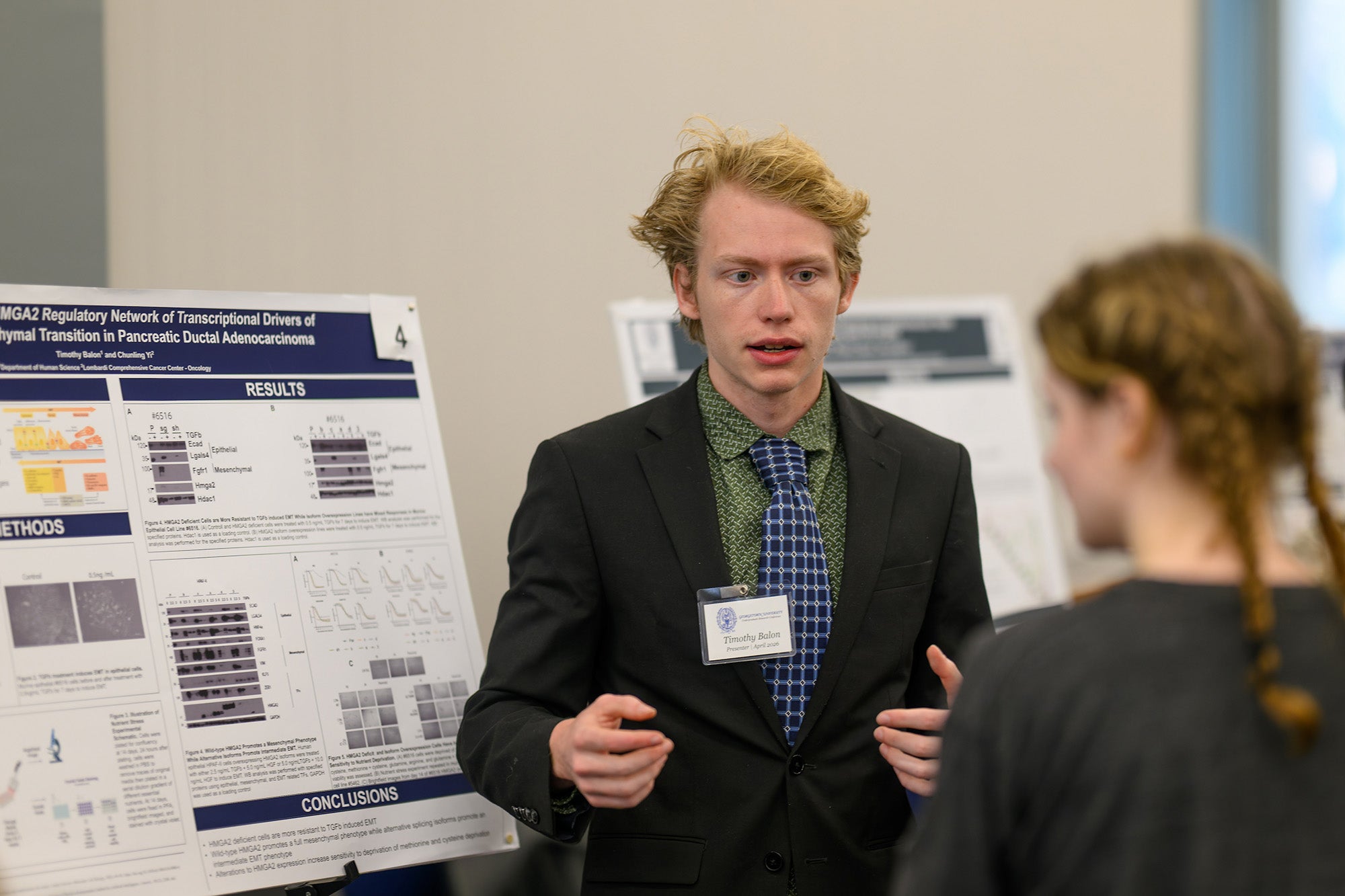 A student explains his poster to a conference attendee