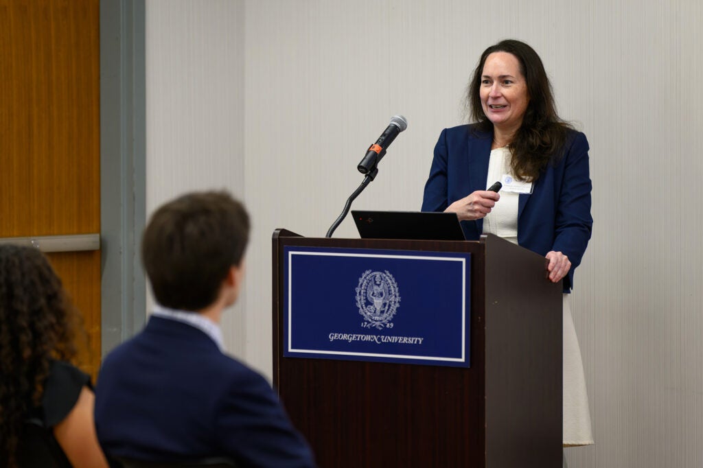 A woman speaks from a podium to an audience