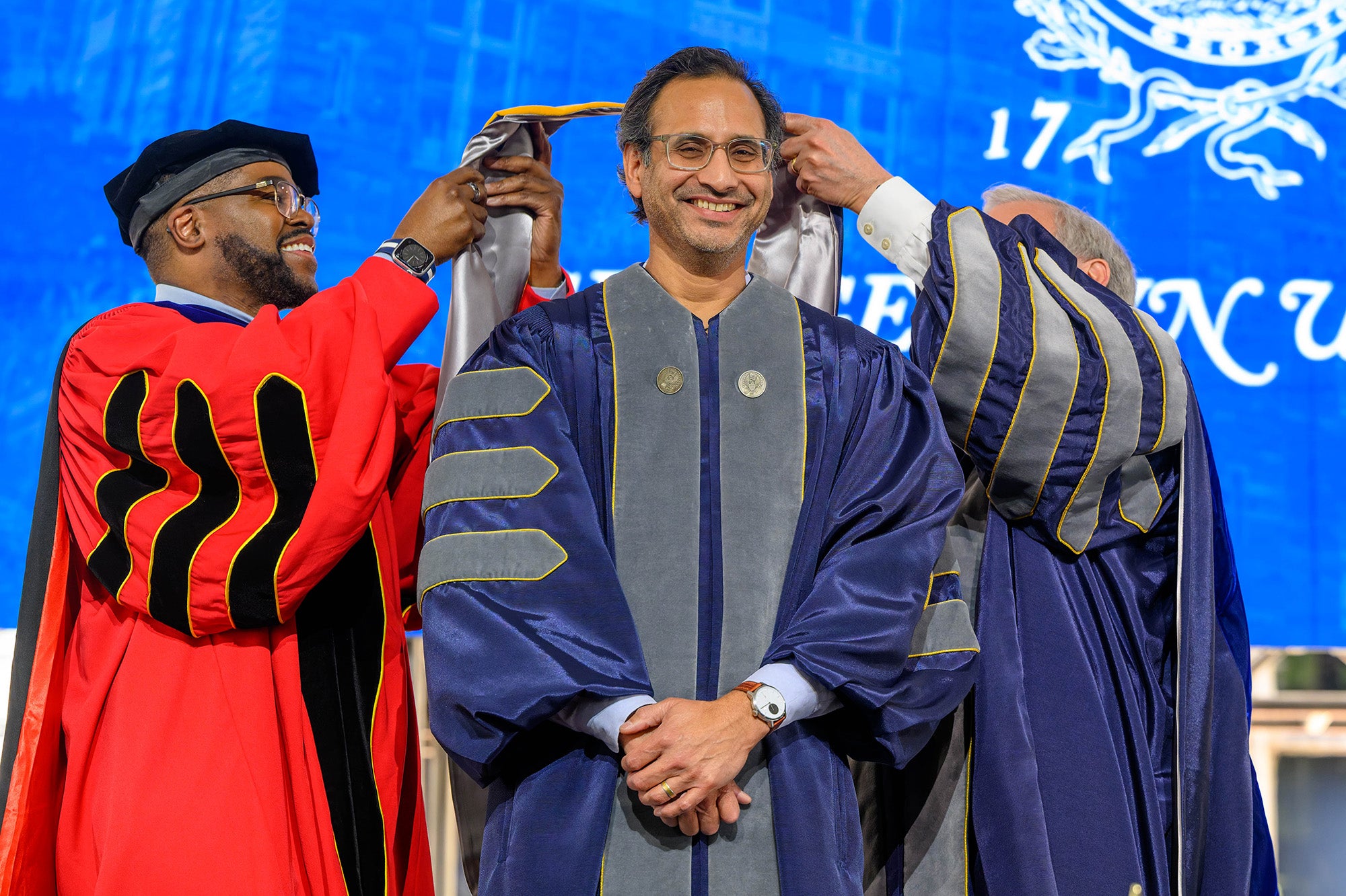 Kedar Mate receives his ceremonial hood from Dean King and Interim President Groves