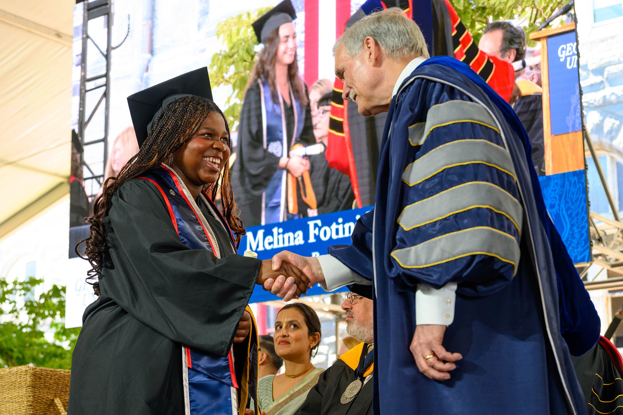 A female student shakes hands with Interim President Groves