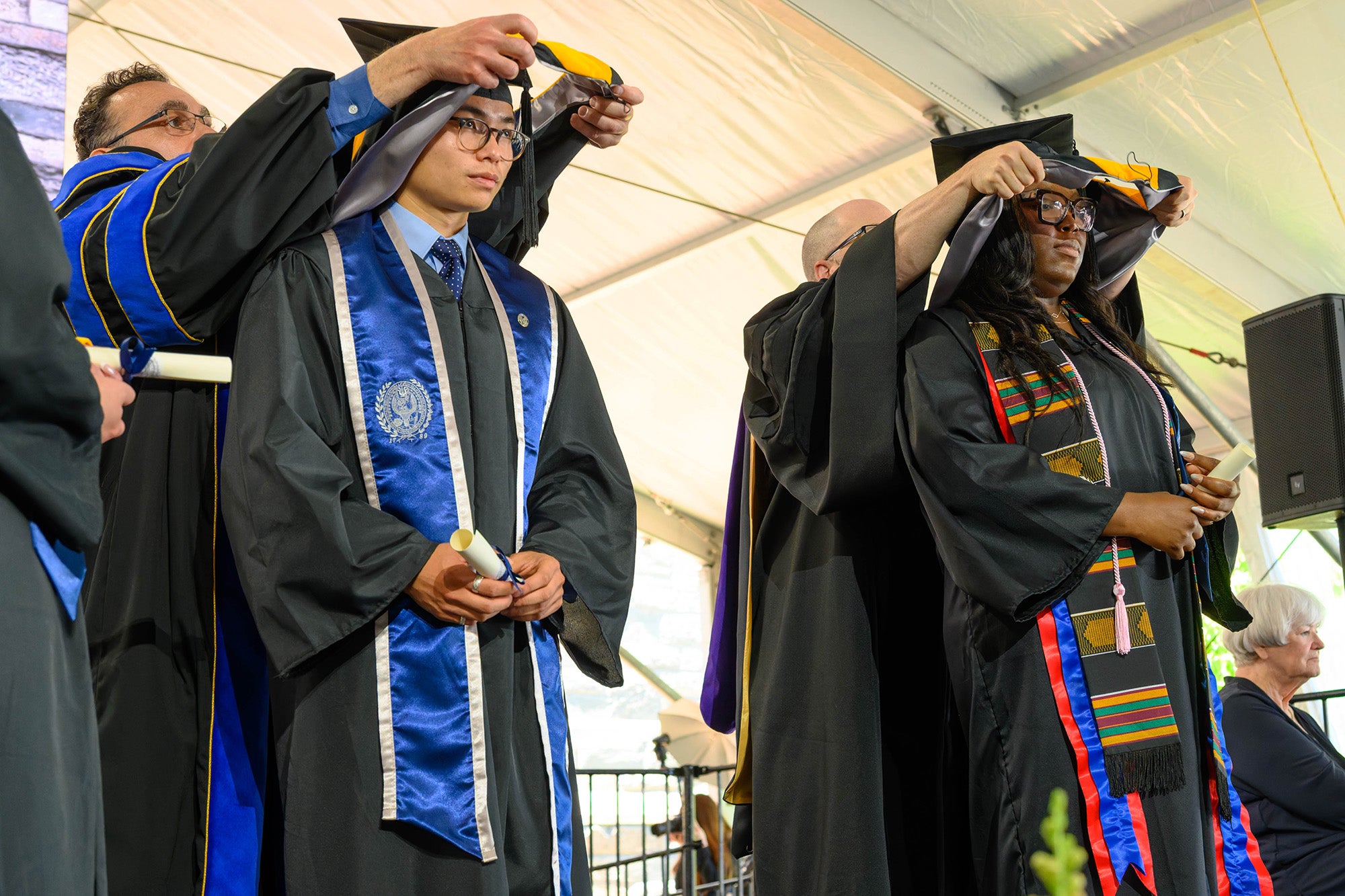 Two graduate students receive their ceremonial hoods