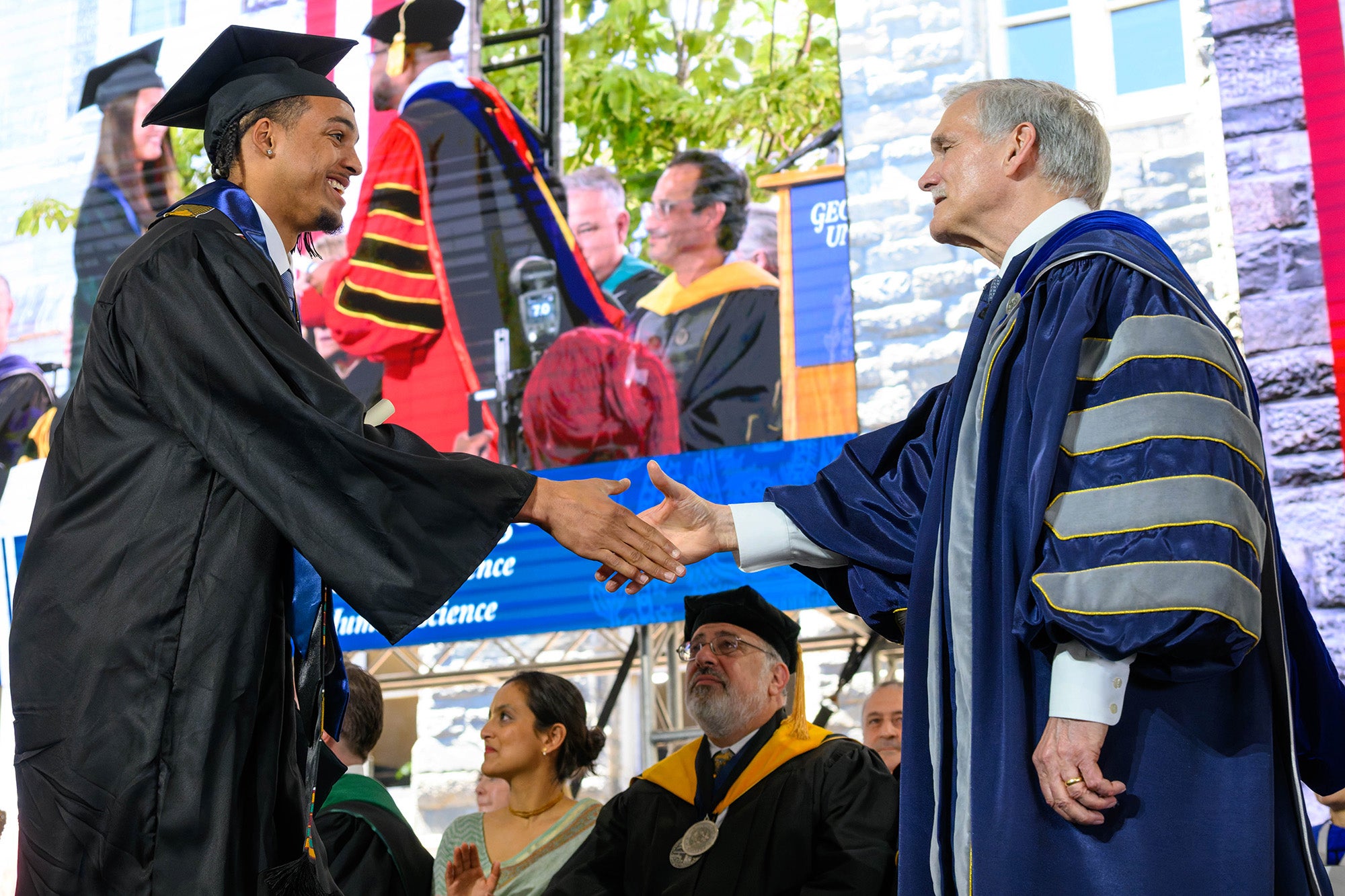 A graduate shakes hands with Interim President Bob Groves