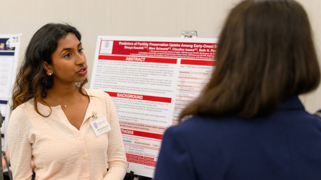 Shreya Kaushik speaks with a participant at the Undergraduate Research Conference about her poster