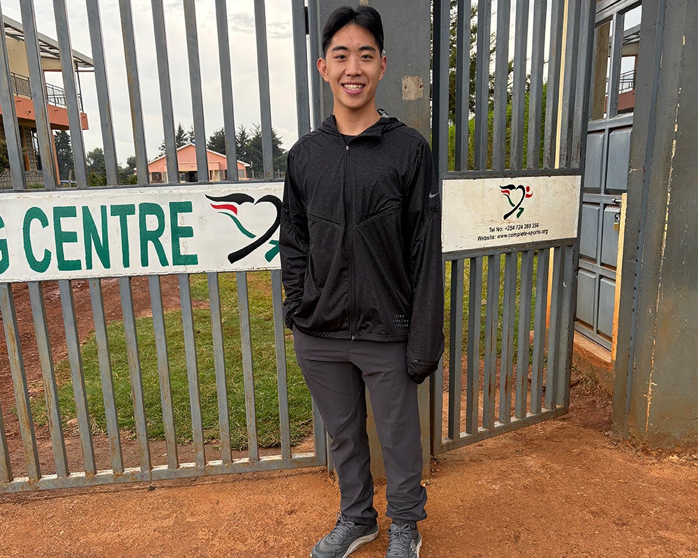 Jordan Pai stands before a gate