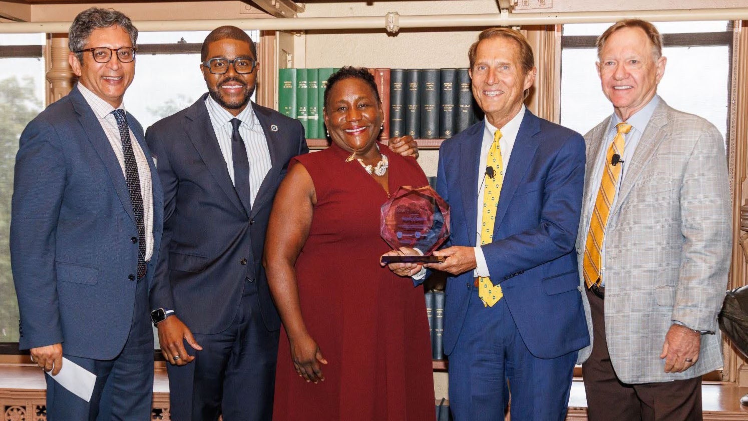 Five leaders standing and smiling as an award is given.